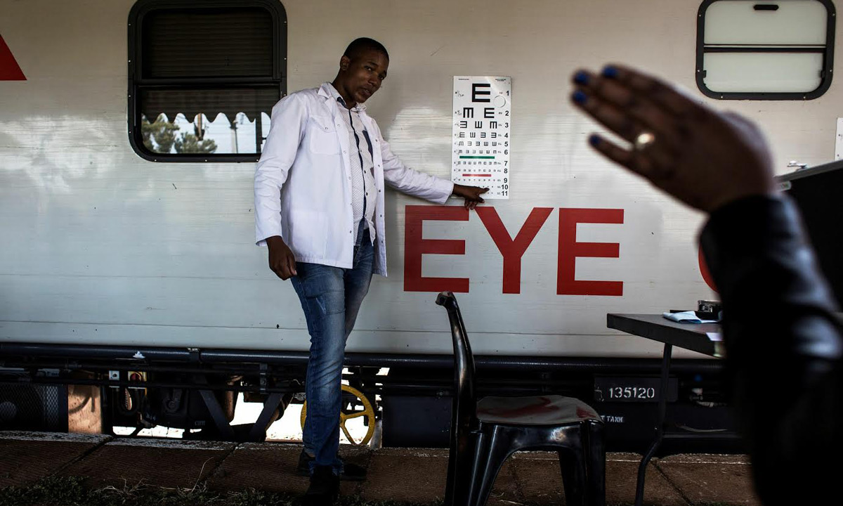 A doctor is seen testing a patients eye sight outside the mobile health train, &quot;Phelophepha&quot;. (AFP)